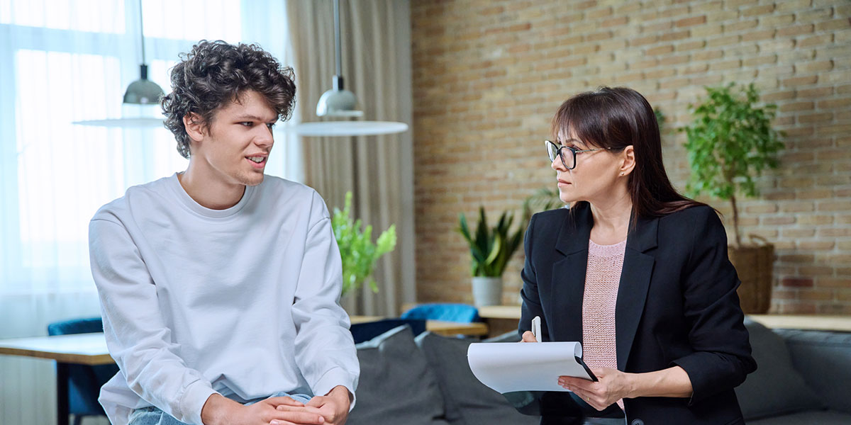 Young man in therapy session discussing his emotional problems with female psychotherapist