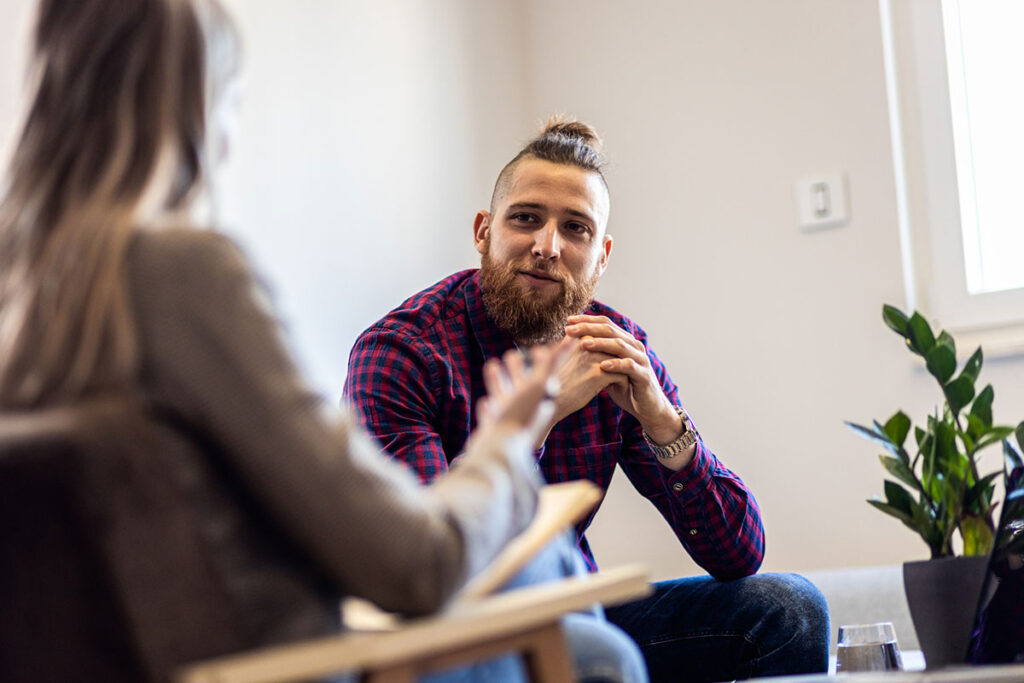 Female psychologist talking to young man during session.