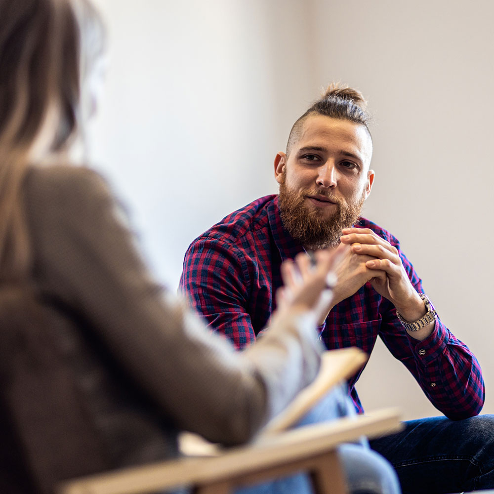 Female psychologist talking to young man during session.