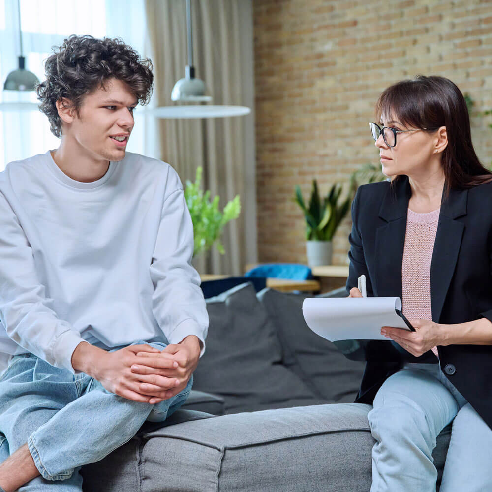 Young man in therapy session discussing his emotional problems with female psychotherapist