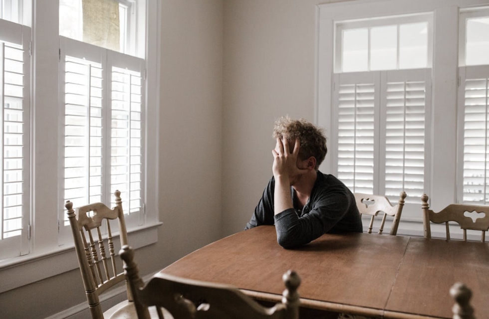 a man sitting at the table and thinking about the Difference Between Burnout and Clinical Depression