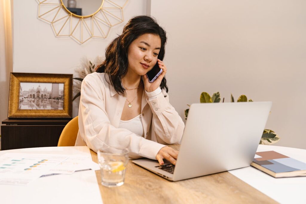 a woman talking on the phone and using a laptop