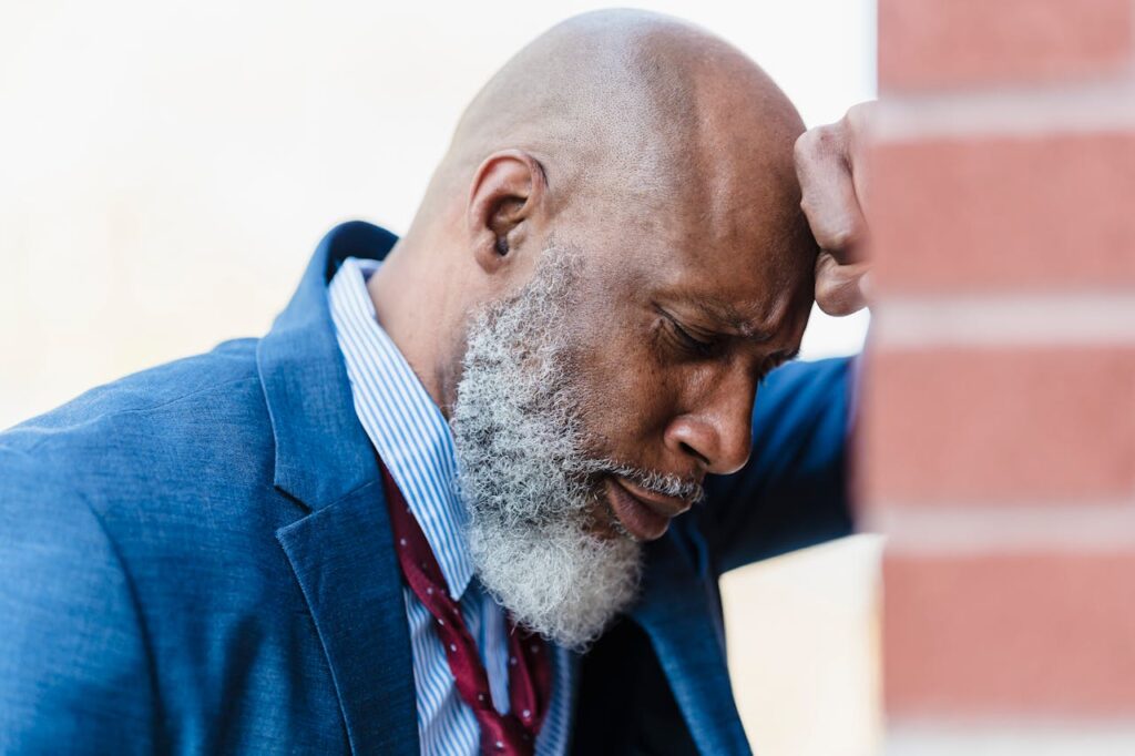 a man with a defeated expression, leaning on a wall contemplating whether he should go to borderline personality disorder treatment massachusetts