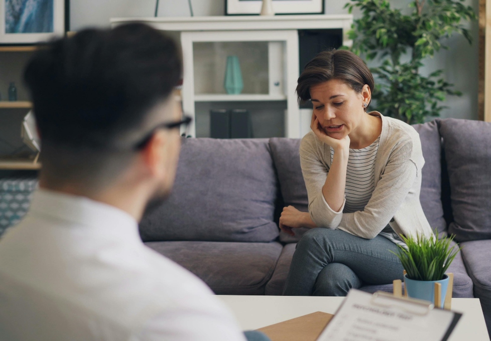 Young woman sitting on a couch, deep in thought, representing the emotional weight of starting therapy with limited time