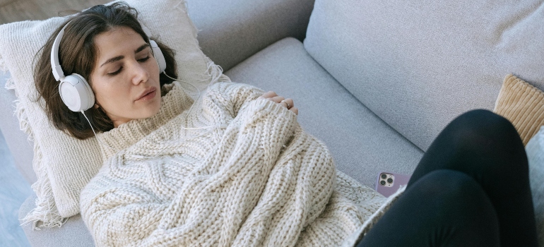 Woman lying on a couch with headphones, practicing mindfulness or reflecting after therapy