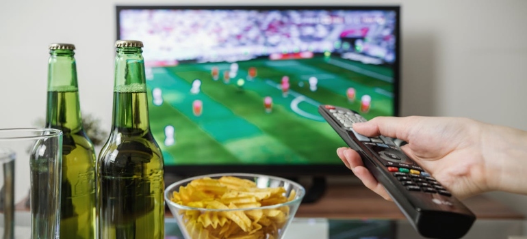 a man with a remote in his hand watching a game on the tv