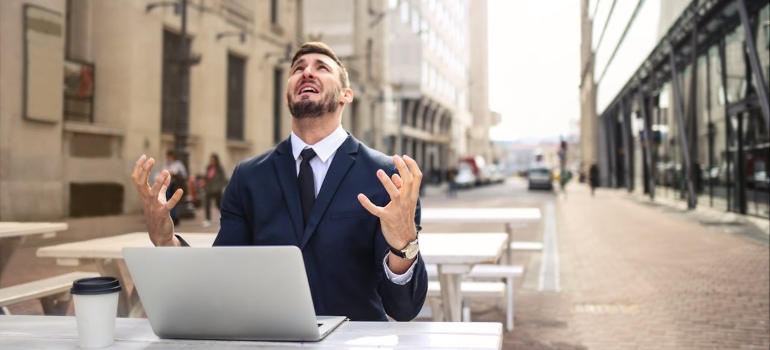 an angry man sitting in front of a laptop outside 