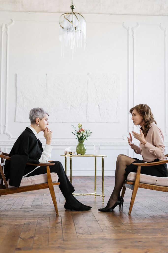 Woman in Black Long Sleeve Shirt Sitting on Brown Wooden Chair in a solution based therapy session
