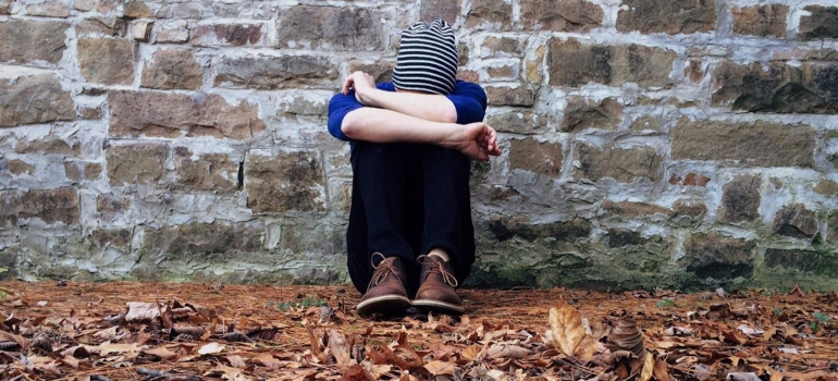 a man sitting on the ground covering his head with his hands 